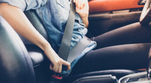 Young driver with car insurance putting on their seatbelt