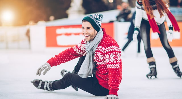 man sitting on ice in ice rink