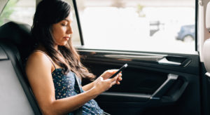 woman in back seat of car looking at cellphone