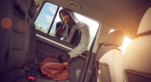 Man stealing a bag out of an unsecured car with the windows down