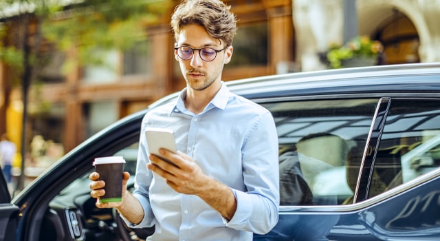 Young man researching on his phone how to switch car insurance companies.